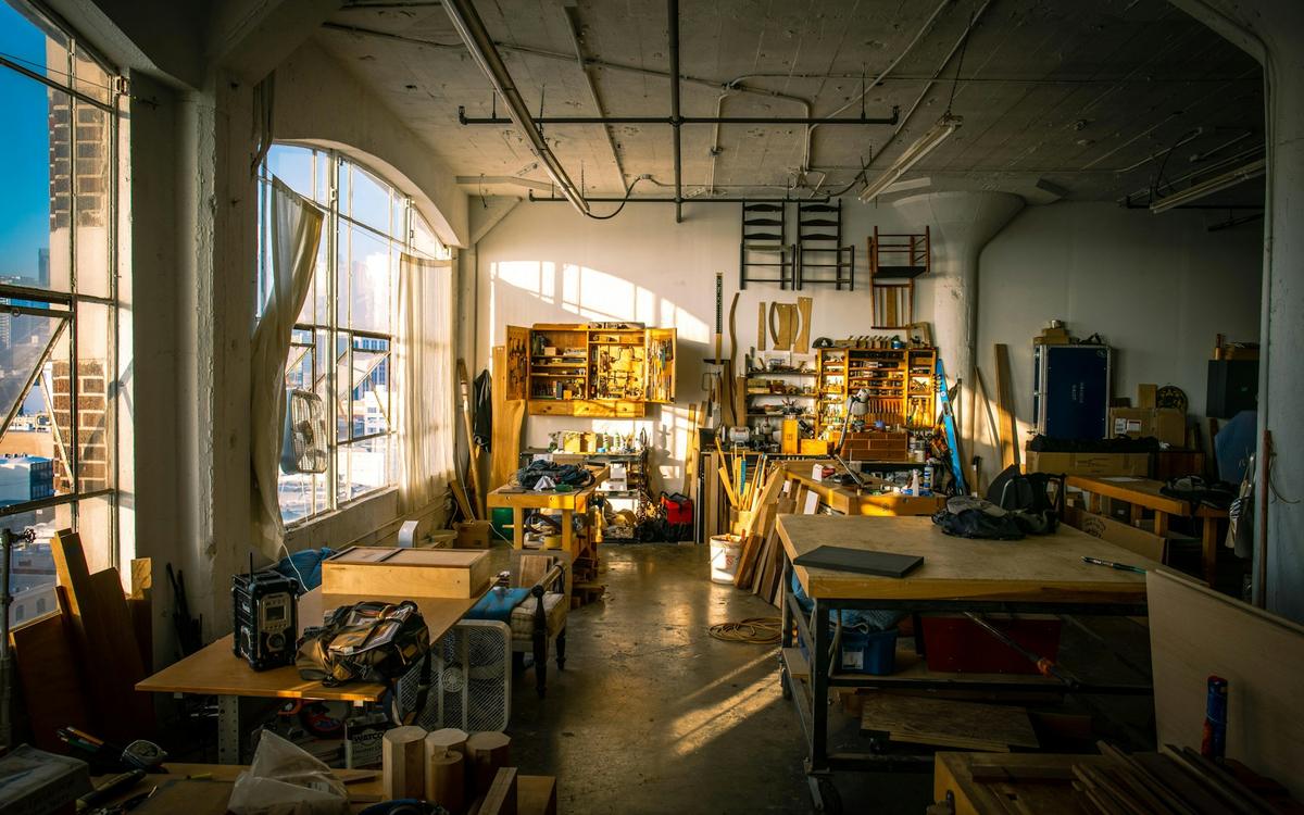 Atelier de tâmplărie cu bancuri de lucru și unelte, în lumină caldă