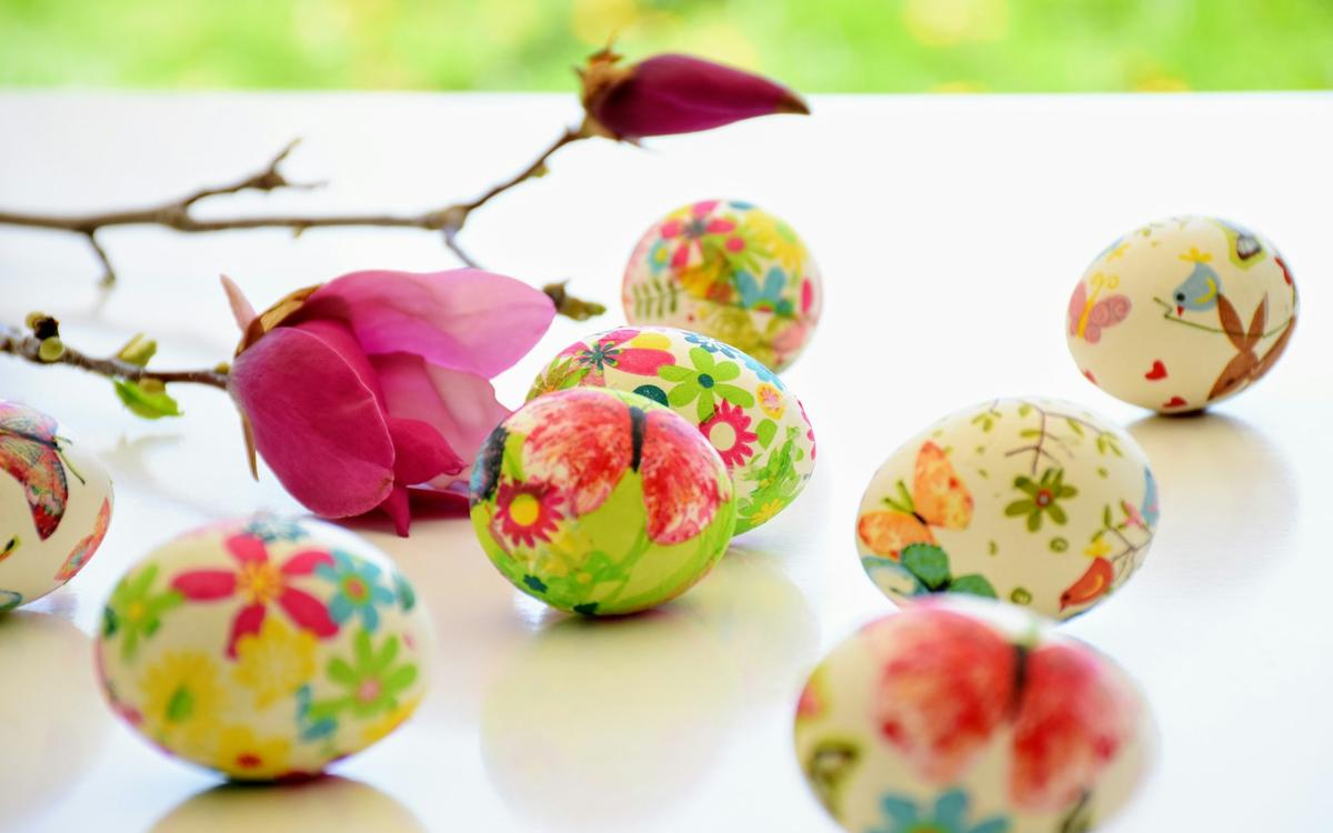 Ouă decorate cu motive florale lângă o creangă cu flori