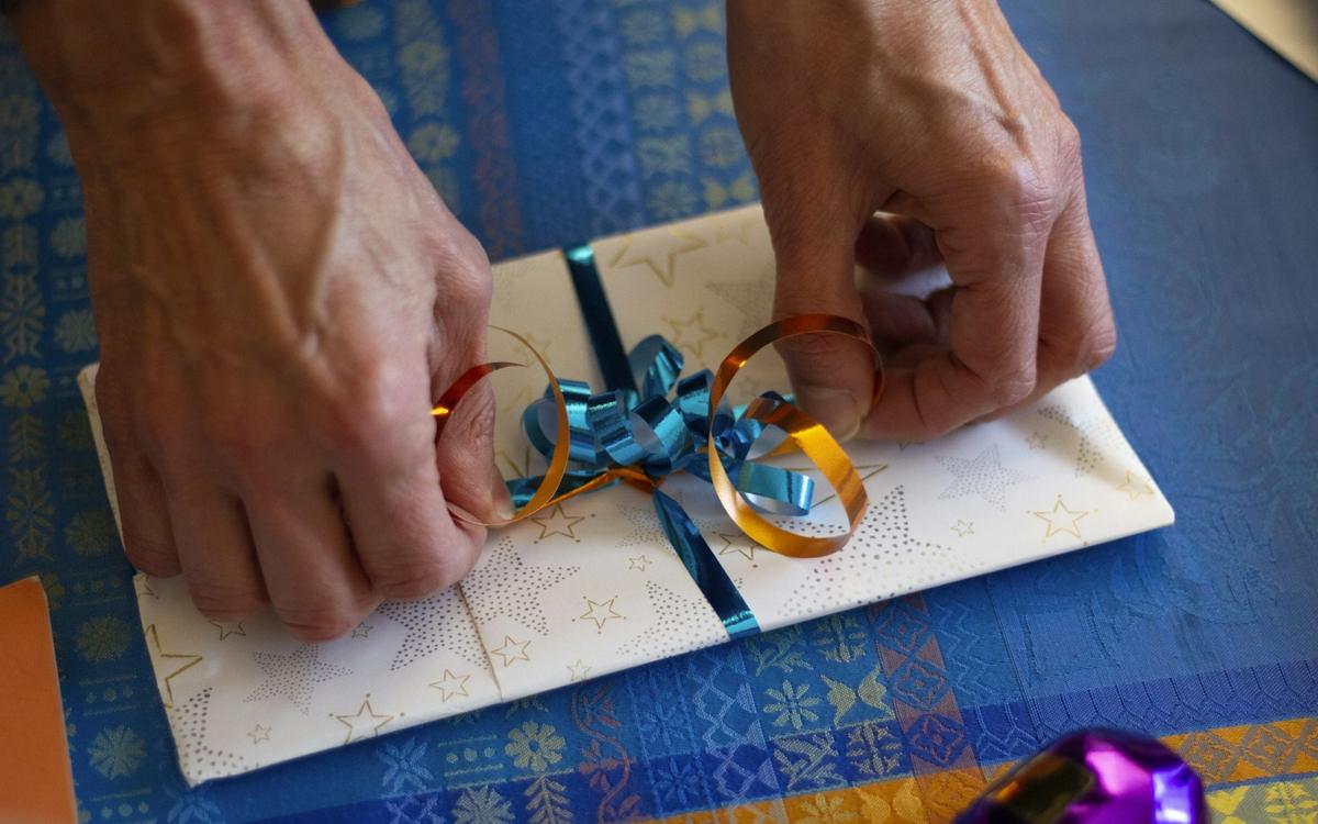 Mâini care leagă o fundă pe o felicitare făcută de mână