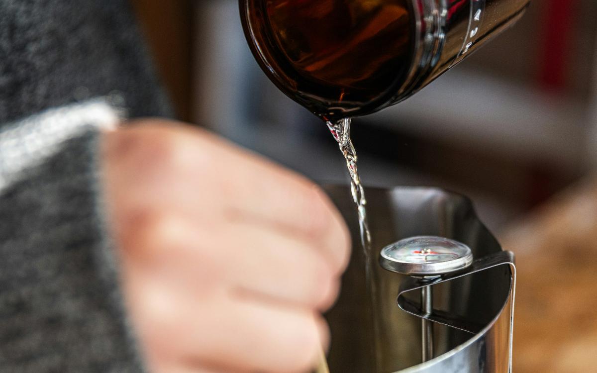 Ceară topită turnată dintr-un vas metalic, cu termometru