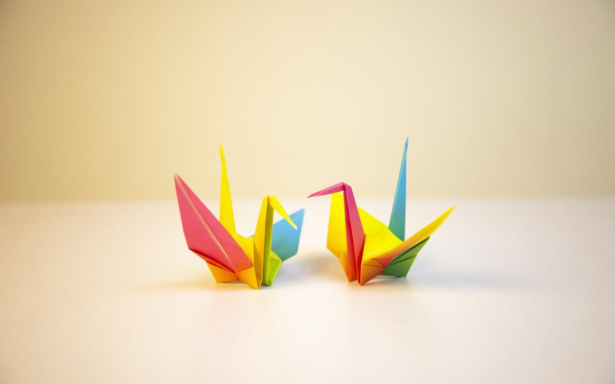 Doi cocori origami colorați pe o masă albă