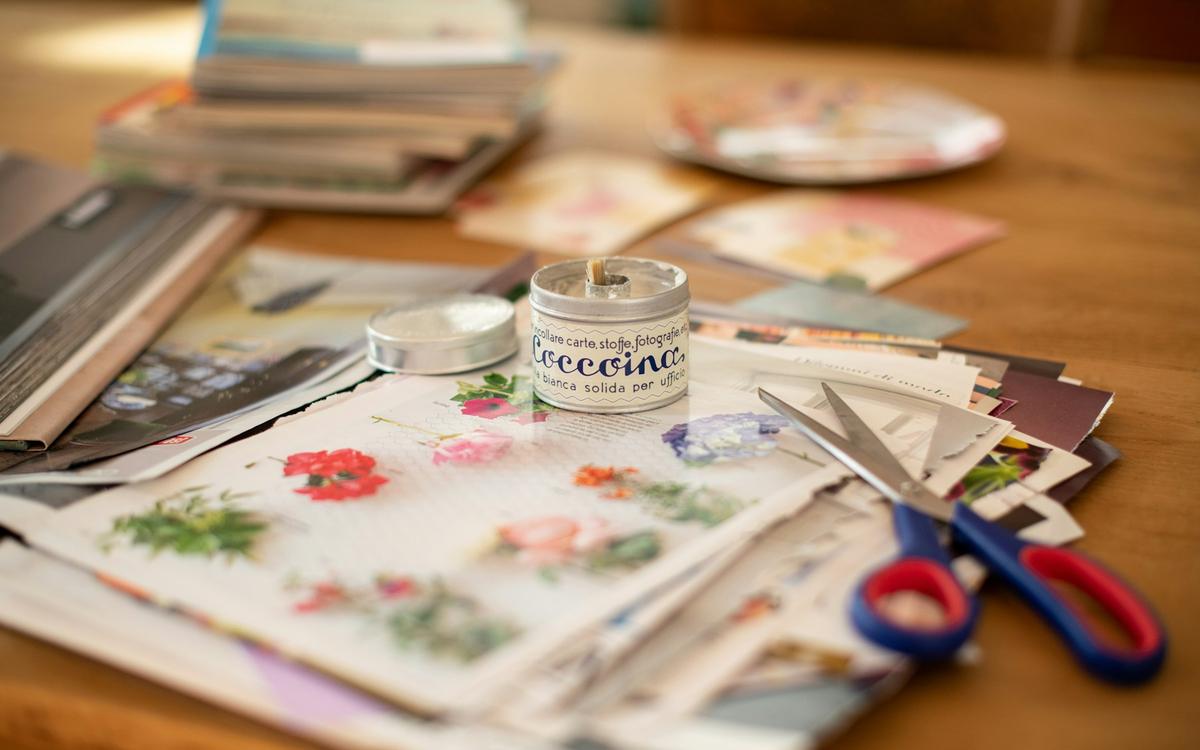 Masă cu hârtii decorative, fotografii, foarfecă și bandă decorativă
