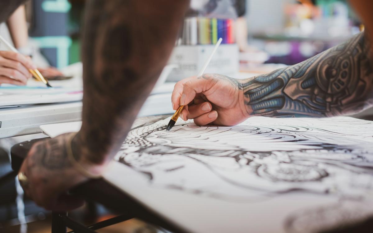 Ilustrator care desenează cu tuș și peniță pe o foaie mare